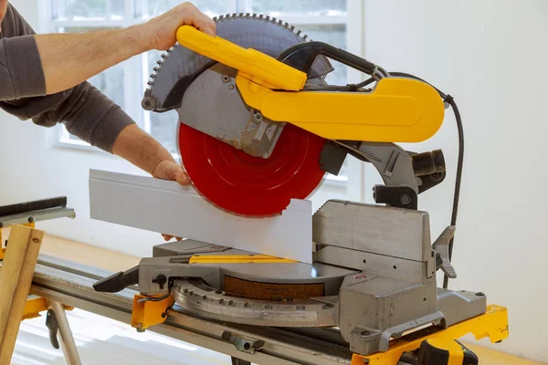 Worker cuts wood baseboard on the power miter saw — Stock Photo, Image