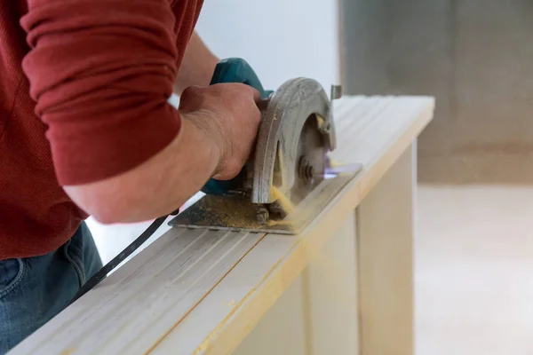 Manos de hombre sosteniendo sierra circular y preparándose para hacer una puerta de madera cortada — Foto de Stock