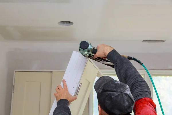 Instalación de puertas de la habitación en la casa trabajador de madera con pistola de clavos —  Fotos de Stock