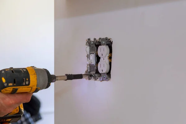 Electrician repairing wall switch indoors