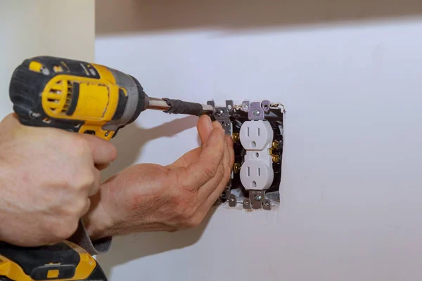 Электрик устанавливает выключатель освещения в стене — стоковое фото