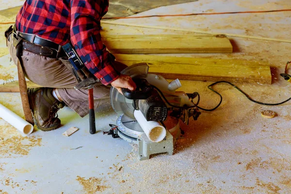 Worker using electric saw cutting pvc pipe in construction new commercial construction