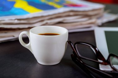 Gazete ve kahve bardağı, okuma gözlükleri ve Not defteri