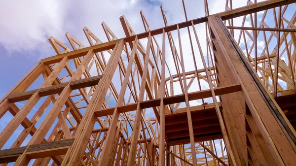 Close-up of beam built home under construction and blue sky with wooden truss, post and beam framework. Timber frame house, real estate background