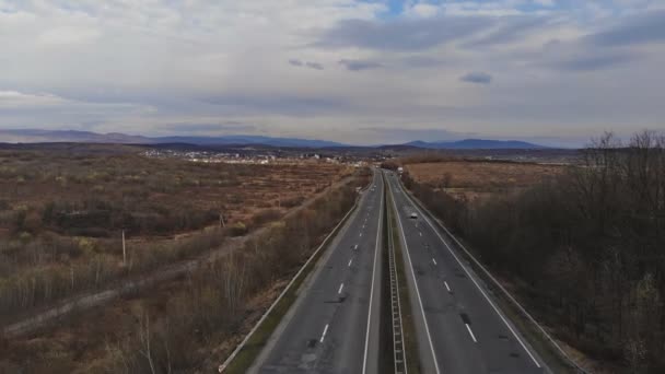 側山の低地を通る道路暗いと重いトーン。道路の両側は不毛で、生い茂った空が曇っている. — ストック動画