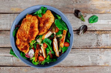 Eski ahşap arka planda taze sebzeler ile ızgara tavuk salatası.