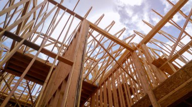 Açık mavi gökyüzünün altında güneş ışığıyla yeni inşaat kirişlerine bakıyorum.