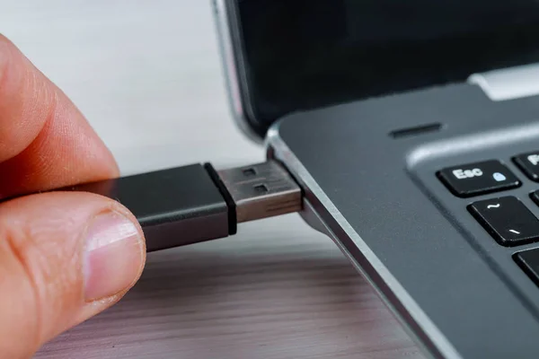 Close up of hand inserting USB flash drive into laptop computer on white background. — Stock Photo, Image