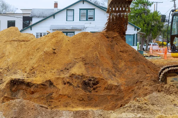 Cavadora amarilla gran excavadora cubo recoger y vierte tierra, piedras en una cantera en las casas de construcción. En construcción — Foto de Stock