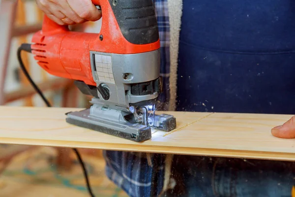 Homem cortando uma prancha com uma máquina de quebra-cabeças serrar placa de madeira — Fotografia de Stock