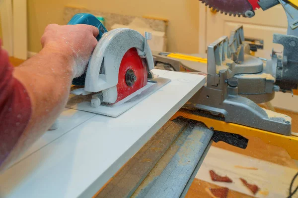 Construction remodeling home cutting wooden trim board on with hand circular saw. — Stock Photo, Image