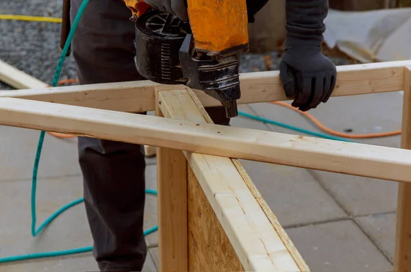 İşçi verandaya çekiç atmak için ahşap döşeme kuruyor