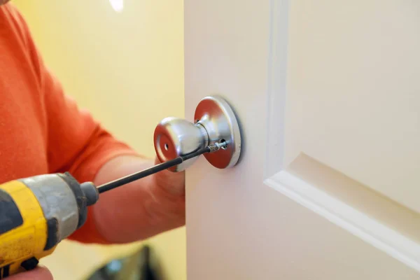 Hombre reparando el pomo de la puerta. primer plano de las manos del trabajador la instalación de nuevo armario de la puerta —  Fotos de Stock