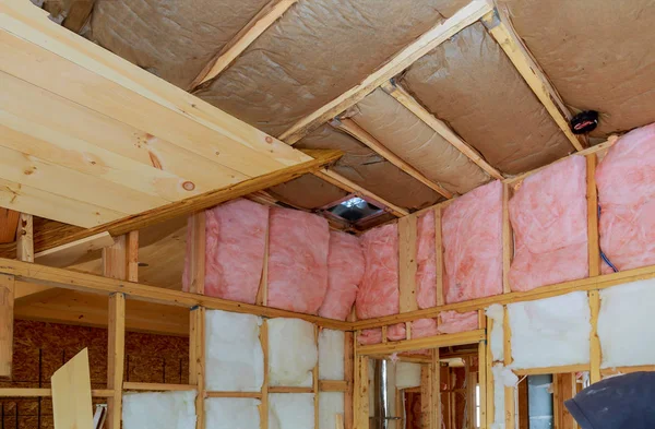 Lana de vidrio mineral en un marco de madera en una pared inclinada cerca del techo de madera en una casa privada . —  Fotos de Stock