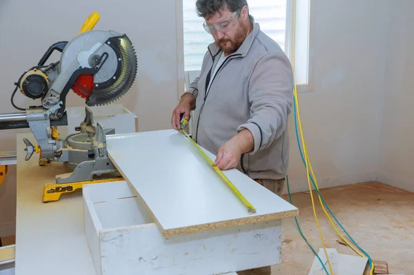 Trabajador del contratista del edificio usando medir y marcar una tabla antes de cortar el estante de madera —  Fotos de Stock