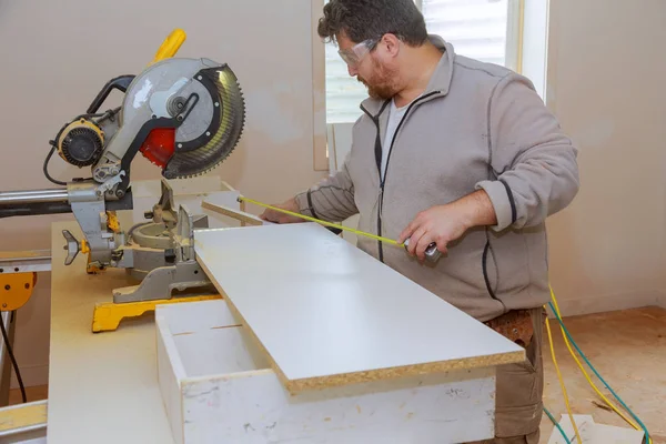 Lavoratori che installano laminato e misurano scaffali bianchi laminati prima di tagliare . — Foto Stock