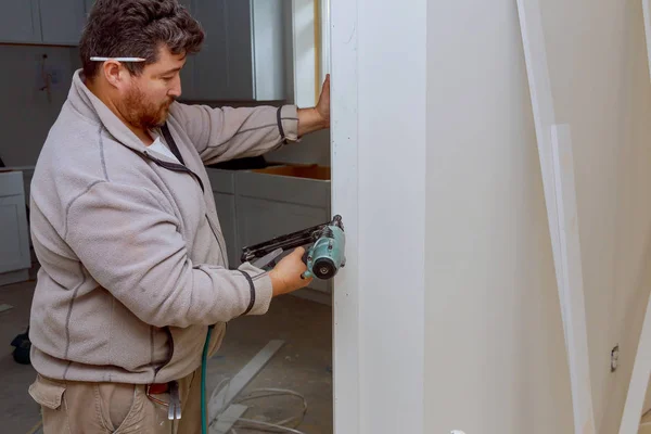 Installation av lister på fragment av gjutning av att använda spikpistol hem förbättringar — Stockfoto