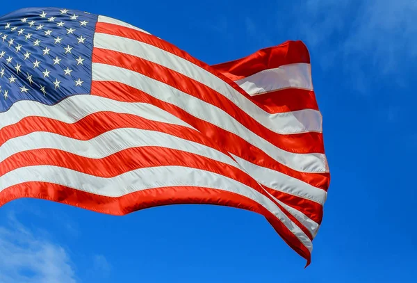 Amerikanska flaggan röd, vit och blå med stjärnor och remsor i vinden blå himmel — Stockfoto