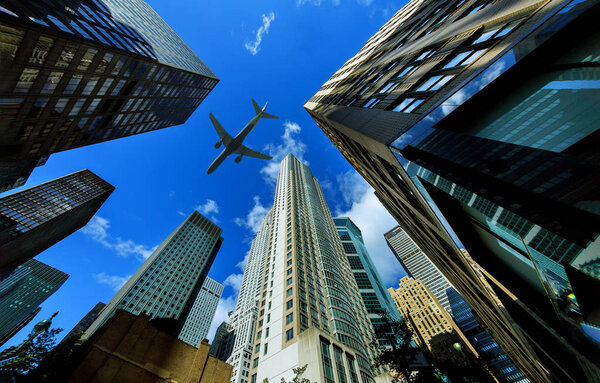 Looking up at New York city skyscrapers in financial district, NYC USA passenger plane flying