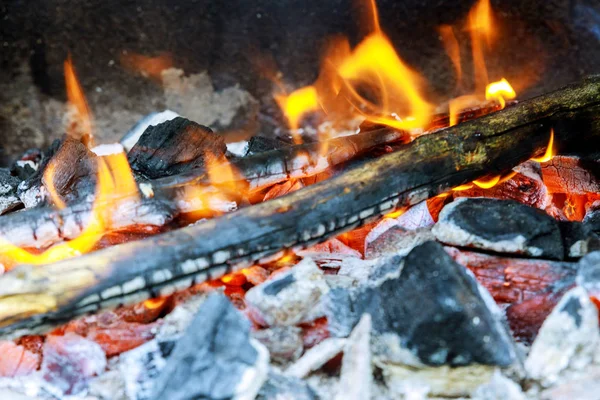 Brennholz brennt in einem Kohlenbecken auf einer leuchtend gelben Flamme ein Baum, dunkelgraue Kohlen in einem Metallkessel. — Stockfoto