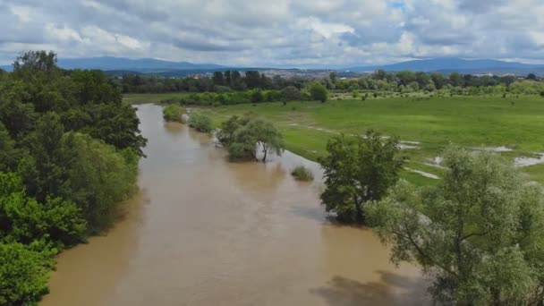 Lantlig by längs flodvatten på höga nivåer med översvämningar ängar en molnig himmel — Stockvideo