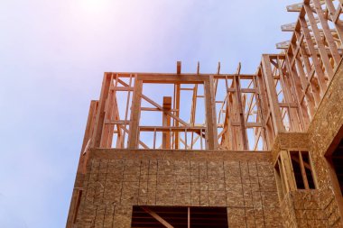 Açık mavi gökyüzünün altında güneş ışığıyla yeni inşaat kirişlerine bakıyorum.