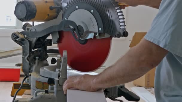 Worker cuts wood baseboard on the power miter saw — Stock Footage Worker cuts wood baseboard on the power miter saw Royalty Free Stock Footage