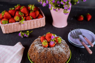 Taze çilek ile ev yapımı bundt kek, tabak, çiçek li vazo.