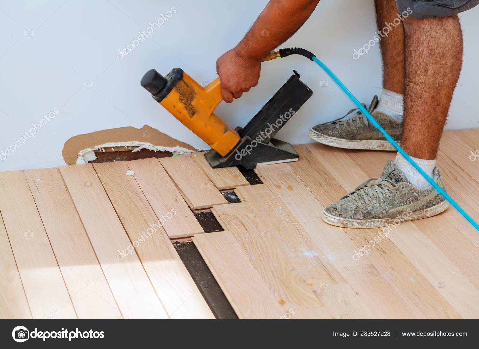 Carpenter Worker Installing Wood Parquet Board With Hammer Stock
