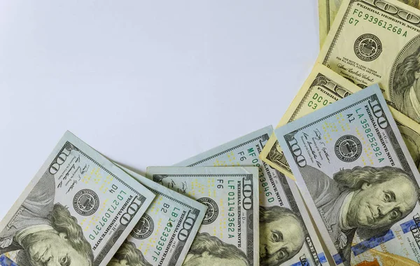 Beyaz arka planda 100 dolarlık banknotların üst görüntüsü.