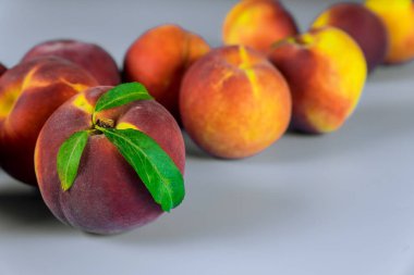 Beyaz arka planda yaprakları olan olgun şeftaliler