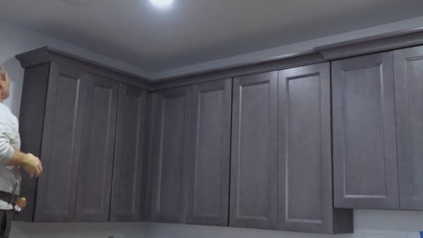 Gabinete de cocina de trabajador negro instalando gabinetes de moldeo de corona de cocina enmarcando el ajuste — Vídeo de stock
