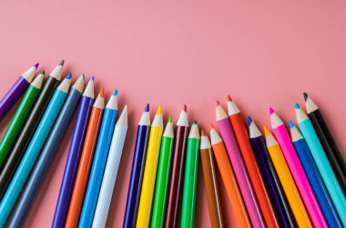 Pembe arka planda izole edilmiş renkli kalemler