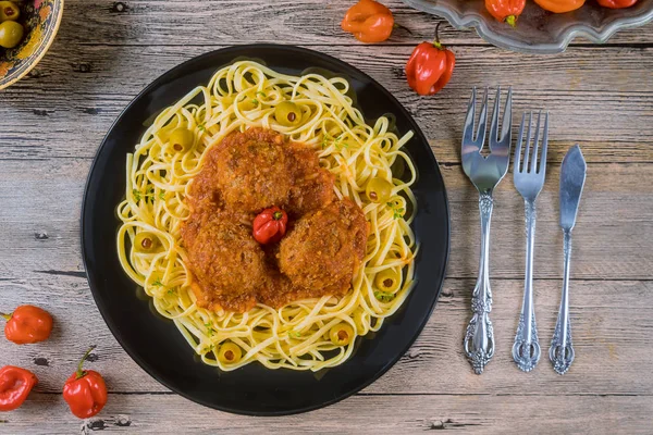 Spaghetti i klopsiki z sosem pomidorowym w czarnym naczyniu na drewnianym tle — Zdjęcie stockowe