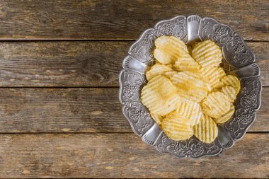 Ahşap arka planda gümüş vintage plaka patates cipsi.