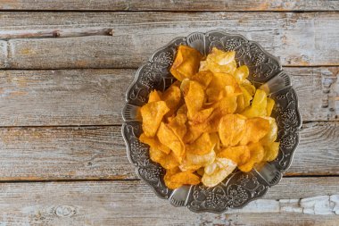 Ahşap arka plan üzerinde karışık patates cipsi Gümüş kase.