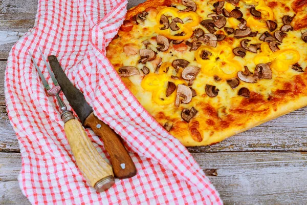 Pizza con cuchillo y toalla sobre fondo de madera . — Foto de Stock