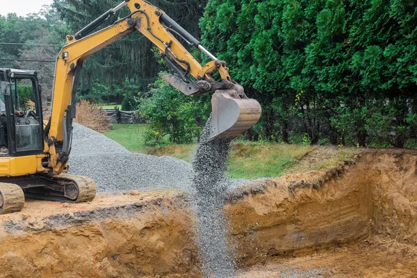 A yellow excavator bucket shovel moving stones gravel of foundation on a construction site — Stock Photo, Image