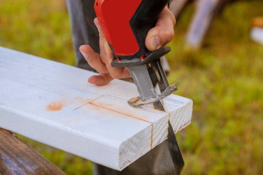 Bir adam testere tozu ile kesme ahşap tahta bir yapboz detay ile ahşap bir tahta kesiyor.