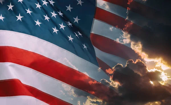 American flag waving in cloudy sky and bright sunrise over the horizon. — Stock Photo, Image