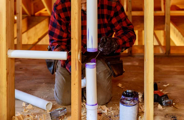 Um encanador aplicando primer e cola um conjunto de dreno de tubo de PVC — Fotografia de Stock