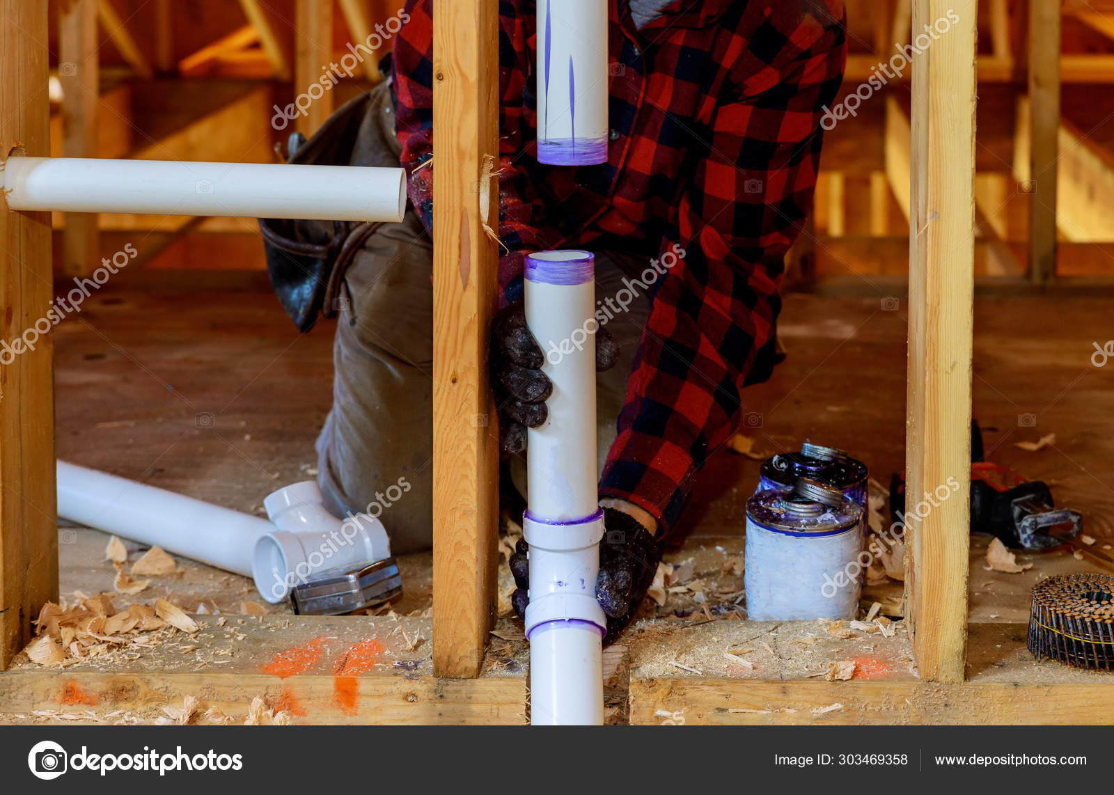Plumber installing primer and glue PVC pipe at construction home Stock