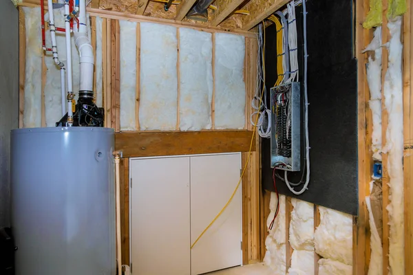 Household boiler house with heat wired electrical terminals on metal bar wall insulation in wooden house, building under construction