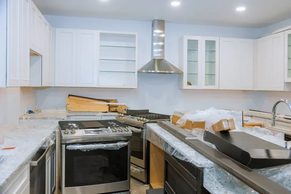 Interior da cozinha moderna com eletrodomésticos na parte superior do fogão, balcão de mármore com armários brancos de cozinha — Fotografia de Stock