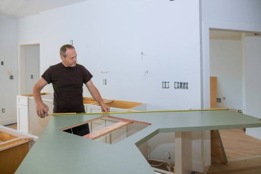 Adam, ahşap mutfak tezgahında ölçü almak için mezura kullanıyor..