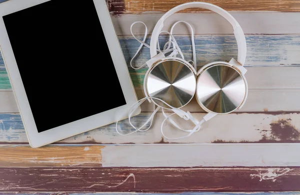 Moderne Kopfhörer und Tablet auf Holztisch. — Stockfoto