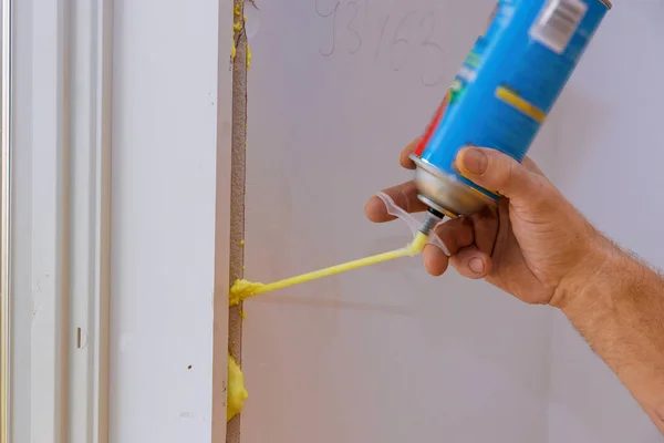 Man using polyurethane foam for installing a window on a handsome worker in action. — Stock Photo, Image