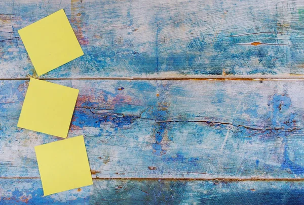Sarı yapışkan notlar boş kare hatırlatıcı mavi eski ahşap arka planda