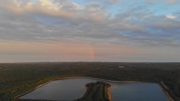 Regenboog in de mooie zonsondergang scène boven een meer met bos hemel — Stockvideo