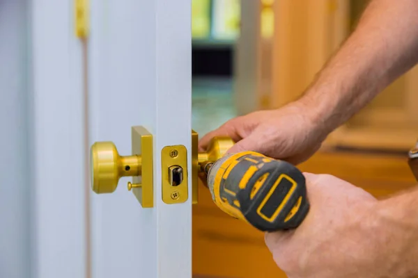 Primer plano de un cerrajero profesional instalando o cerradura nueva en una puerta de la casa con destornillador —  Fotos de Stock